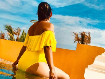 Rear view of woman standing at beach against sky