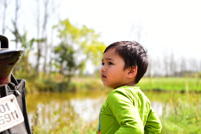 Side view of boy looking away while standing on field