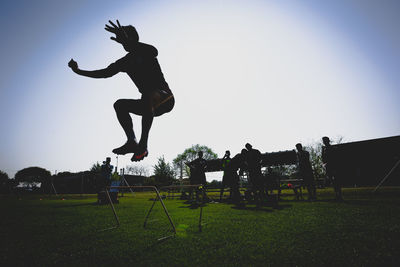 Full length of silhouette man jumping on field against clear sky