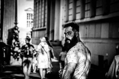 Portrait of mid adult man standing on city street against building