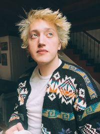 Young man looking up while sitting at home