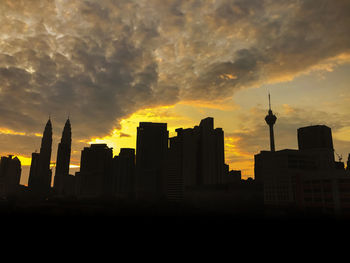 Silhouette of buildings against cloudy sky during sunset