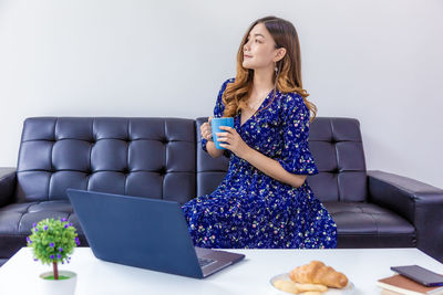 Young woman using mobile phone while sitting on sofa