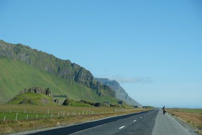 Road by mountains against clear blue sky