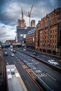 Vehicles on road in city against sky