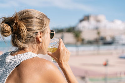 Rear view of woman drinking water from sunglasses