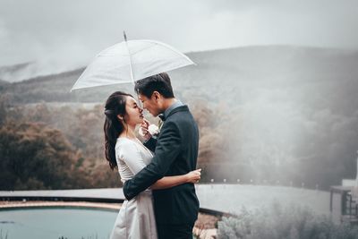 Side view of woman with umbrella standing in rain