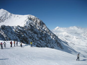 People skiing on snowcapped mountain against sky