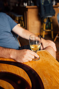 Midsection of man drinking, holding a fluted glass of basque cider in a bar