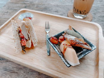 High angle view of sandwich and friuts with icing sugar.