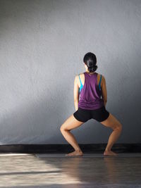 Full length rear view of woman practicing yoga in fitness studio