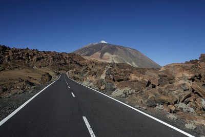 Street amidst rocks on field against blue sky