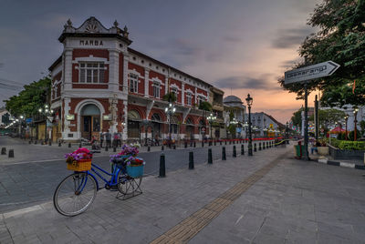 Bicycles parked on road by building against sky