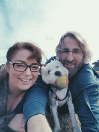 Portrait of smiling woman with dog against sky