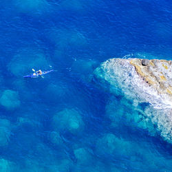 High angle view of person kayaking by rock formation at sea