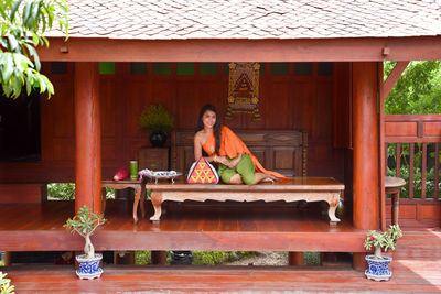 Portrait of woman sitting on table against building