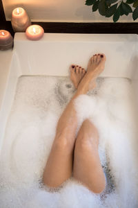 Low section of woman relaxing in bathtub 