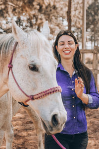 Smiling young woman with horse at ranch