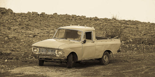 Abandoned car on field against clear sky