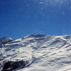 Scenic view of snowcapped mountains against blue sky