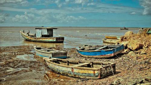 Boats moored on sea shore against sky