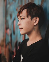 Side view of teenage boy leaning on wall