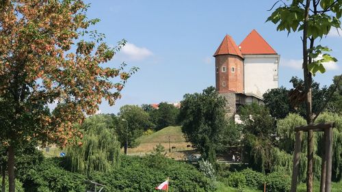 House amidst trees and buildings against sky