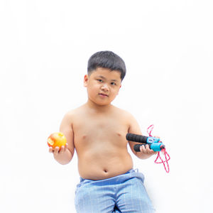 Cute boy holding toy while standing against white background