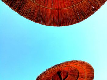 Low angle view of red umbrella against clear blue sky