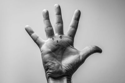 Cropped hand with anthropomorphic face against gray background