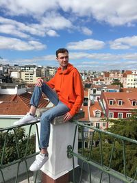 Man standing by railing against buildings in city