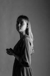 Girl looking away while standing against gray background