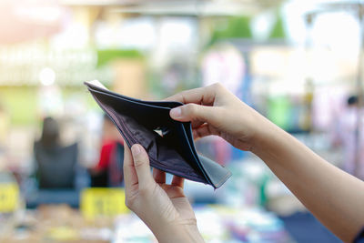 Close-up of woman holding empty wallet outdoors