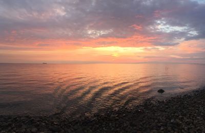 Scenic view of sea against dramatic sky during sunset