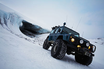 Customised suv standing in front of glacial ice cave on glacier