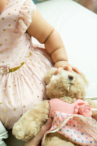 Cute baby girl lying on bed with doll