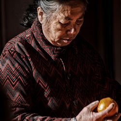 Close-up of senior woman holding fruit at home