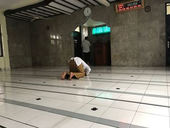 Rear view of man sitting on floor in illuminated building