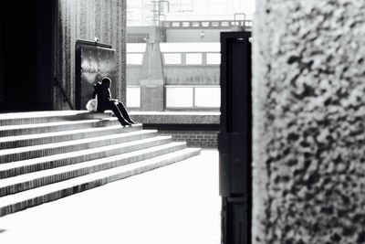 Side view of person sitting on staircase against building