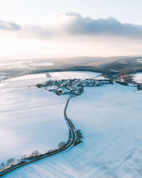 Scenic drone photo of village by snowcapped mountains against sky