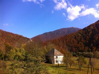 House on field by mountain against sky