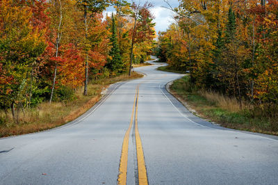 Road amidst autumn trees against sky