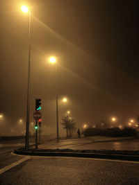 Illuminated street lights against sky at night