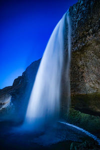 Scenic view of waterfall against clear blue sky