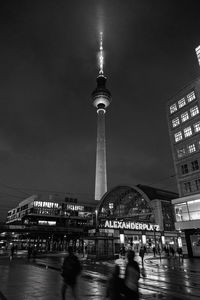 Communications tower in city against sky at night