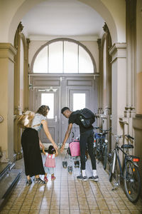 Full length of mother and father assisting daughter in walking at corridor