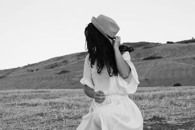 Woman in hat on land against clear sky