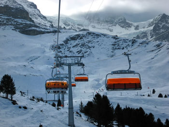 Ski lift over snowcapped mountains against sky