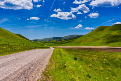 Road amidst field against sky