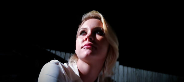 Close-up portrait of young woman against black background